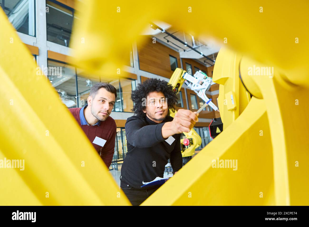 Ingenieure untersuchen und testen einen Greiferarm-Roboter in einer modernen Laborumgebung mit Schwerpunkt auf Industrieautomatisierung und Robotik. Stockfoto