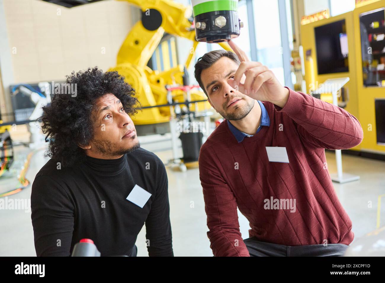 Zwei Ingenieure analysieren eine Roboterhand während einer Schulung, die sich auf industrielle Robotik und Automatisierung konzentriert. Stockfoto