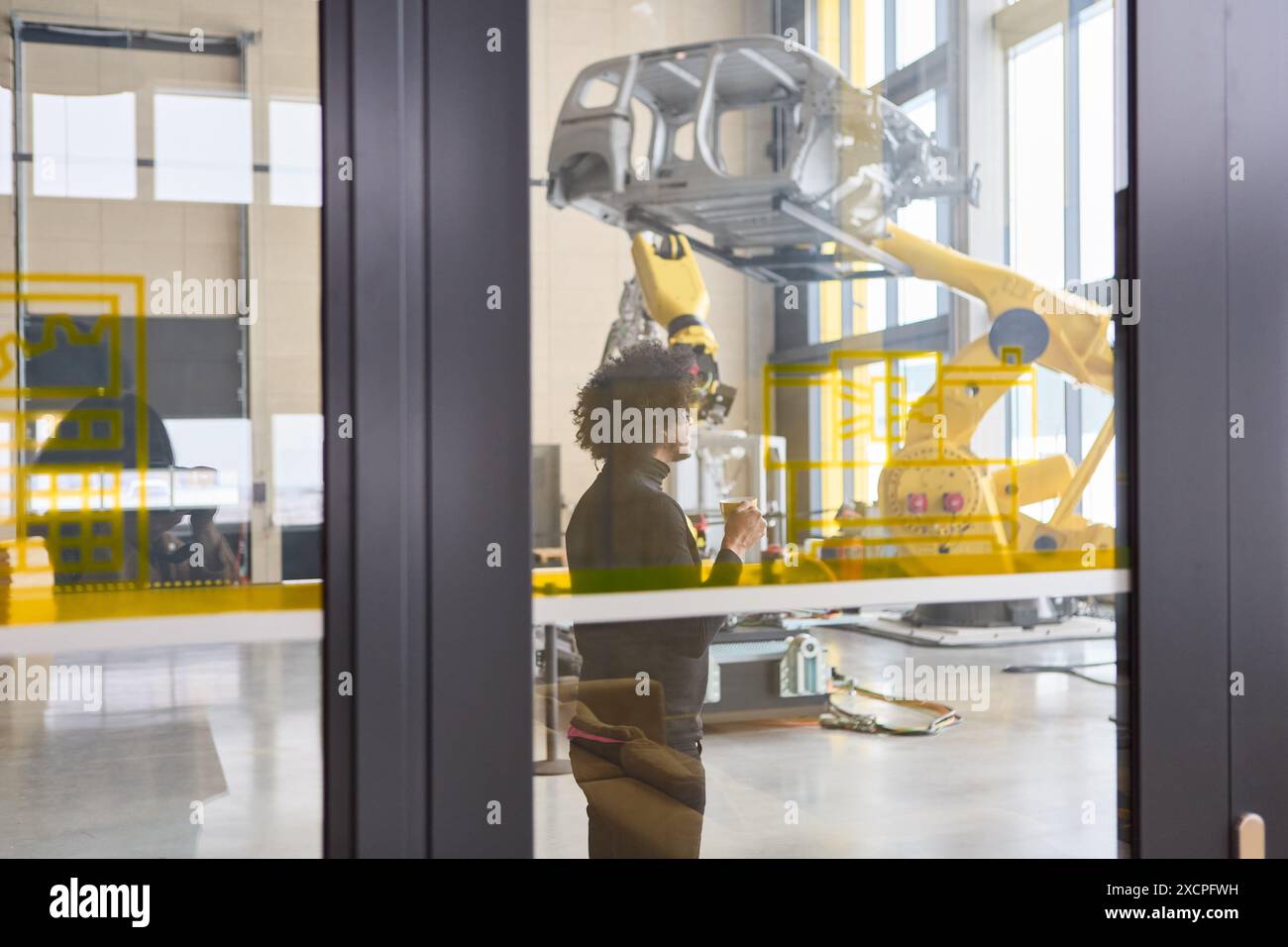 Ingenieur in einem modernen Robotiklabor, der an der Programmierung und Inspektion von Roboterarmen für die Produktions- und Prozessautomatisierung arbeitet. Stockfoto