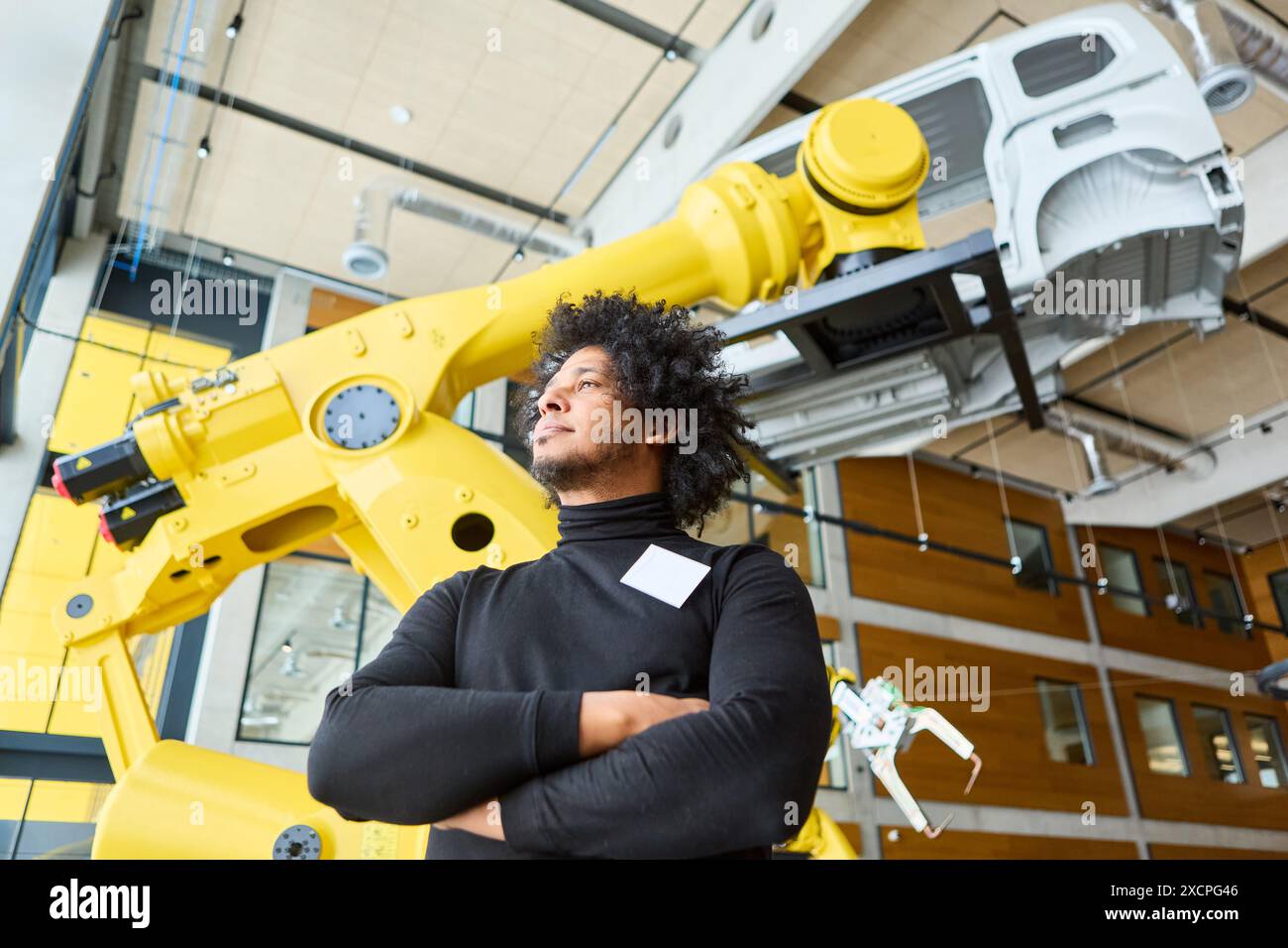 Ingenieur, der einen großen gelben Roboterarm für die Prozessautomatisierung in einer industriellen Umgebung überwacht. Stockfoto