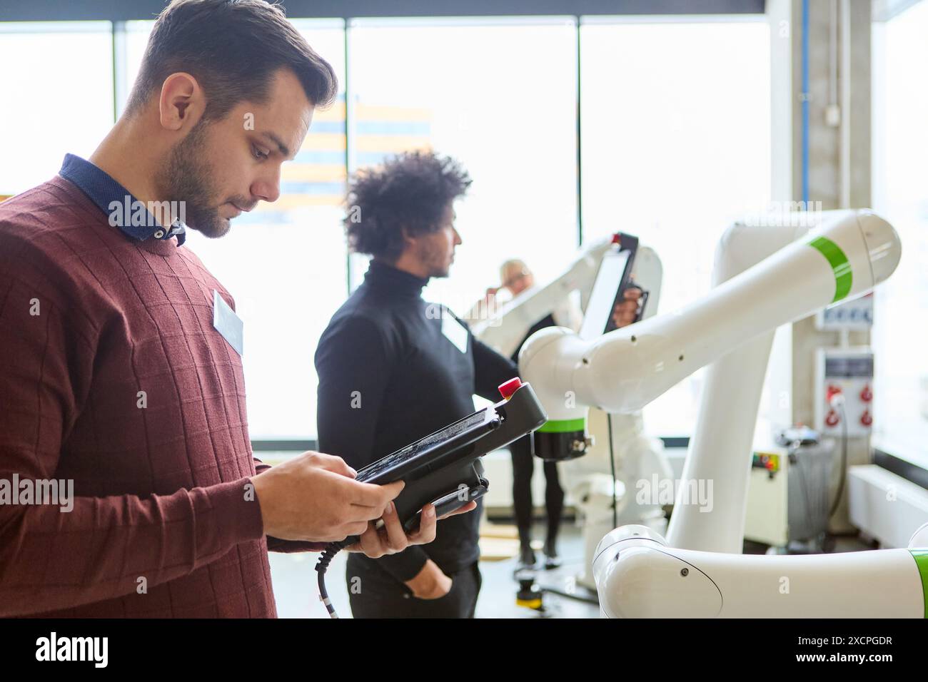 Ingenieure arbeiten an der Programmierung von Roboterarmen in einer modernen industriellen Umgebung und stellen Technologie und Automatisierung vor. Stockfoto