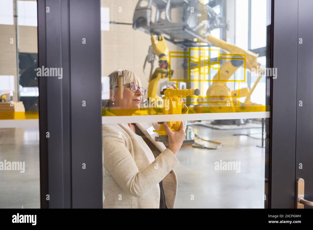 Weibliche Ingenieurin, die einen Roboterarm in einem industriellen Umfeld programmiert und Automatisierung und Technologie in Produktionsprozessen vorstellt. Stockfoto