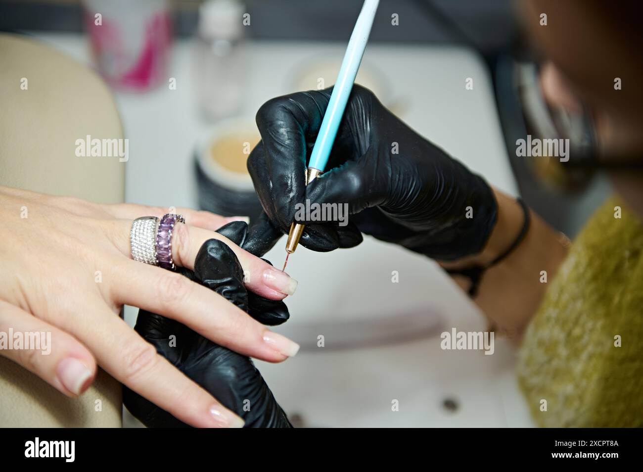 Nahaufnahme eines professionellen Manikürers, der nagellack in einem Schönheitssalon aufträgt und sich auf präzise Details und Kundenbetreuung konzentriert. Stockfoto