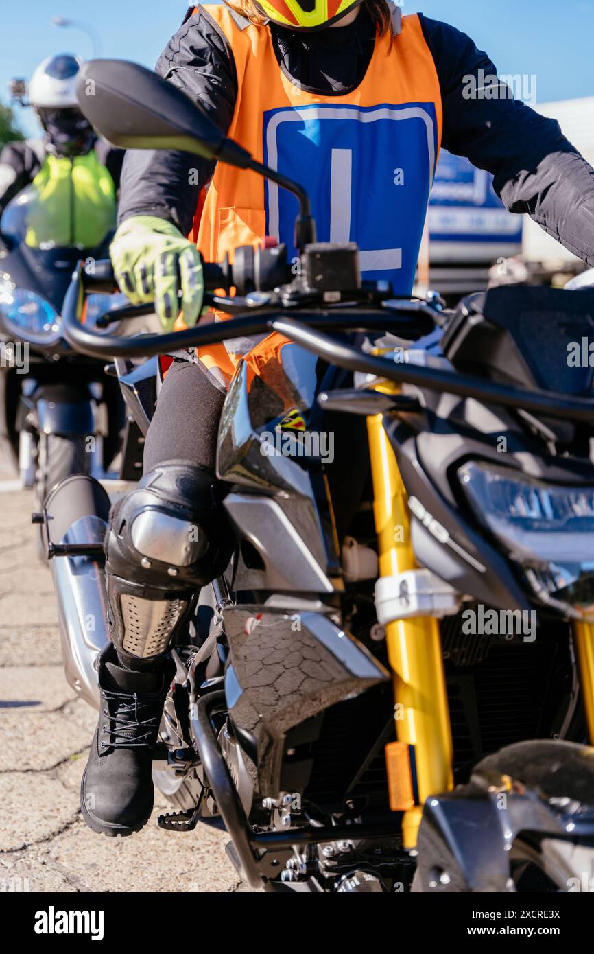 Ein Mann in schwarzer Jacke und orangefarbener Weste fährt Motorrad Stockfoto