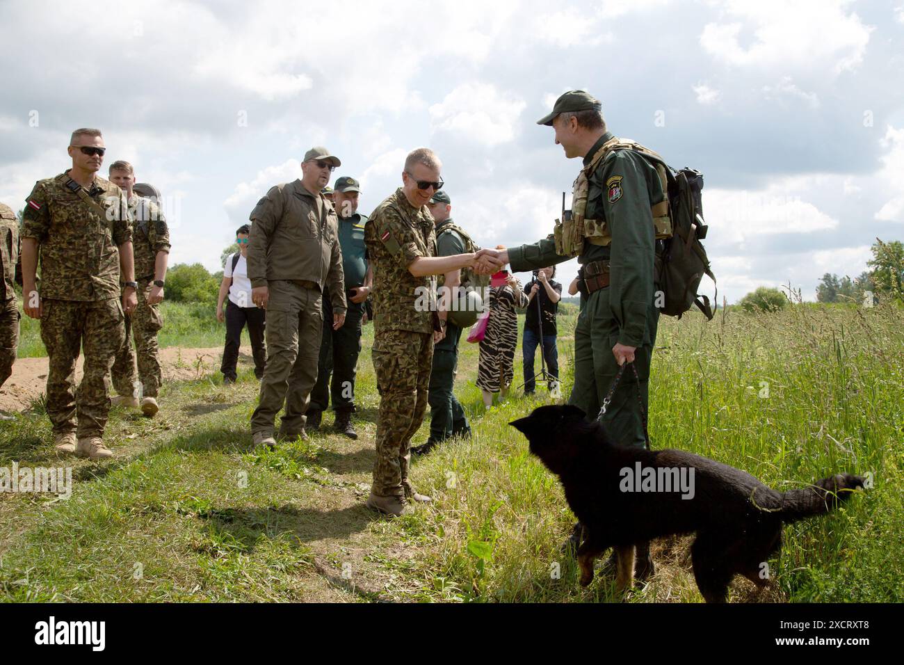 Karsava, Lettland. Juni 2024. Der lettische Präsident Edgars Rinkevics (M) spricht mit einem Grenzschutzbeamten (r) am Grenzzaun an der Grenze Lettlands zu Russland. Quelle: Alexander Welscher/dpa/Alamy Live News Stockfoto