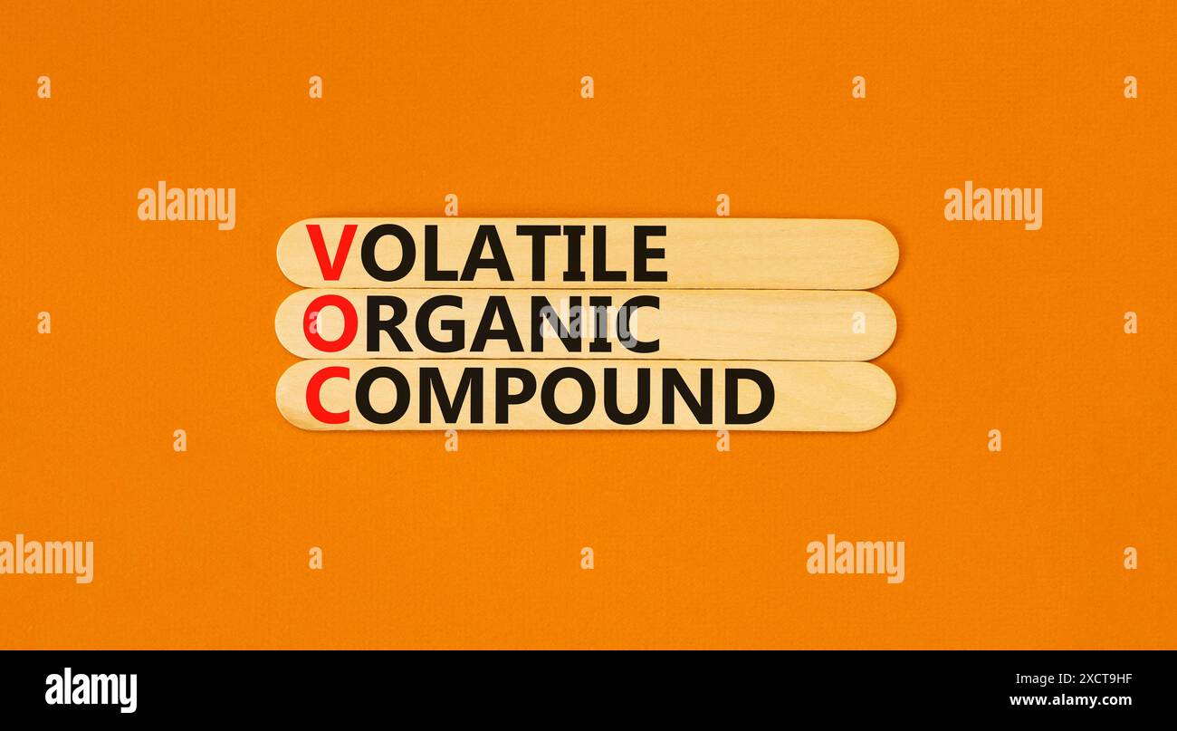 VOC-Symbol für flüchtige organische Verbindungen. Konzeptworte VOC flüchtige organische Verbindung auf wunderschönem Holzstab. Wunderschöner orangefarbener Hintergrund. Geschäftliche VOC Stockfoto