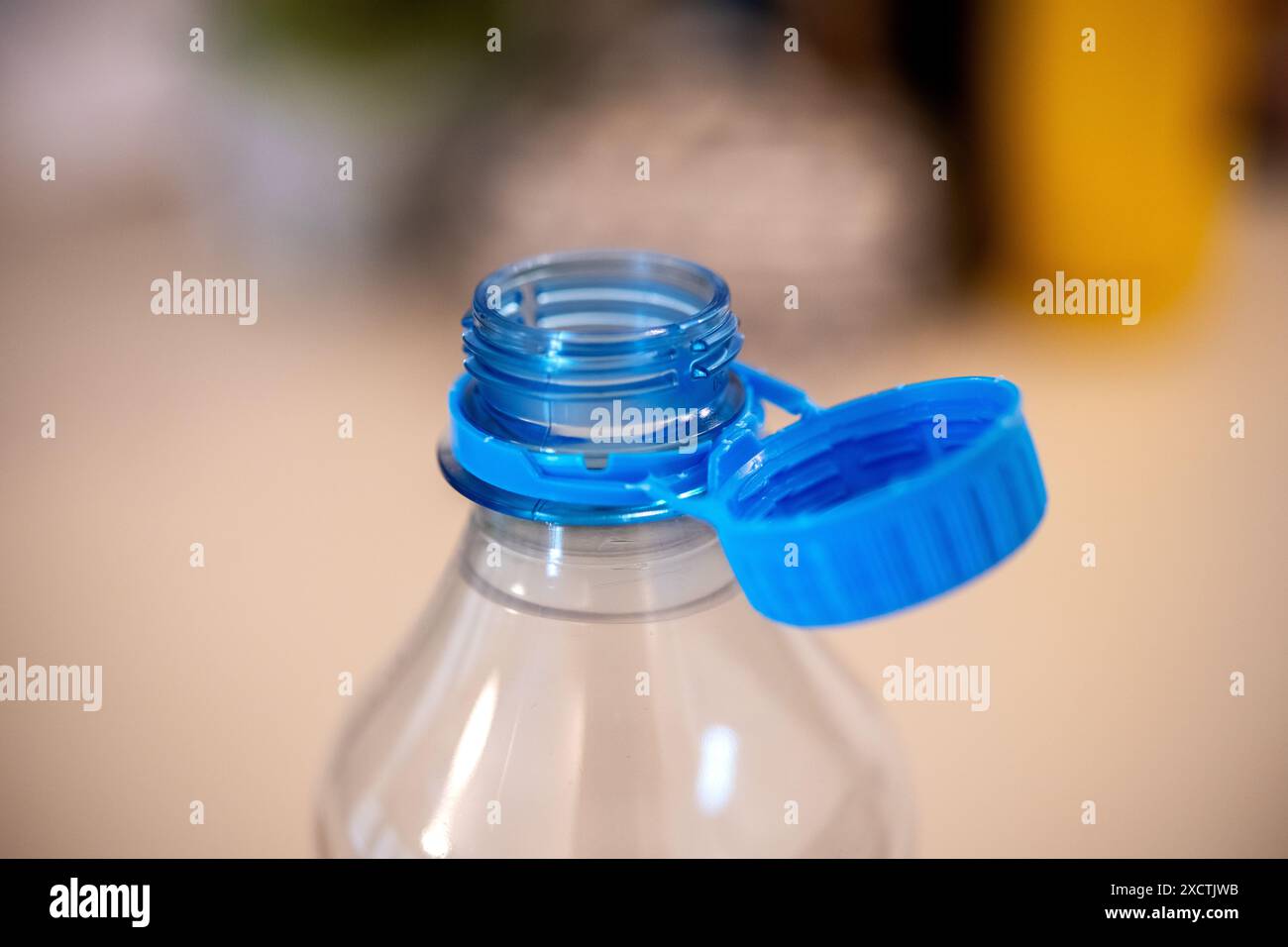 Bei einer Nahaufnahme handelt es sich um einen blauen Schnürverschluss, der an einer transparenten Wasserflasche befestigt ist und die neuen Umweltpolitiken der EU zur Reduzierung der Emissionen hervorhebt Stockfoto