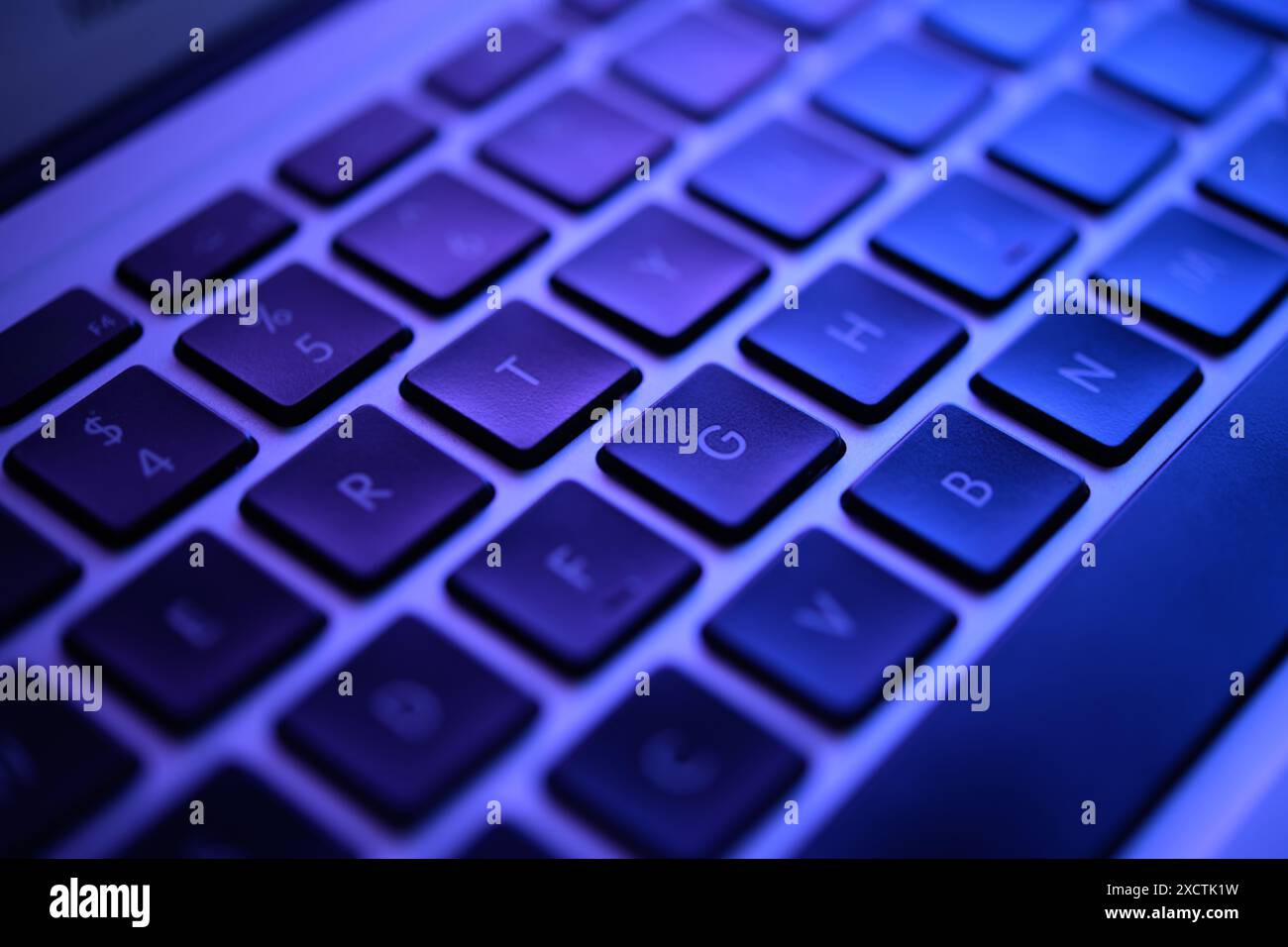 Eine schwach beleuchtete Tastatur leuchtet in unheimlichem Grün und erinnert an die Höhle eines Hackers. Schlüssel mit Warnungen zu Datenmissbrauch, Malware-Codes und Sicherheitslücken, angespannte Szene Stockfoto