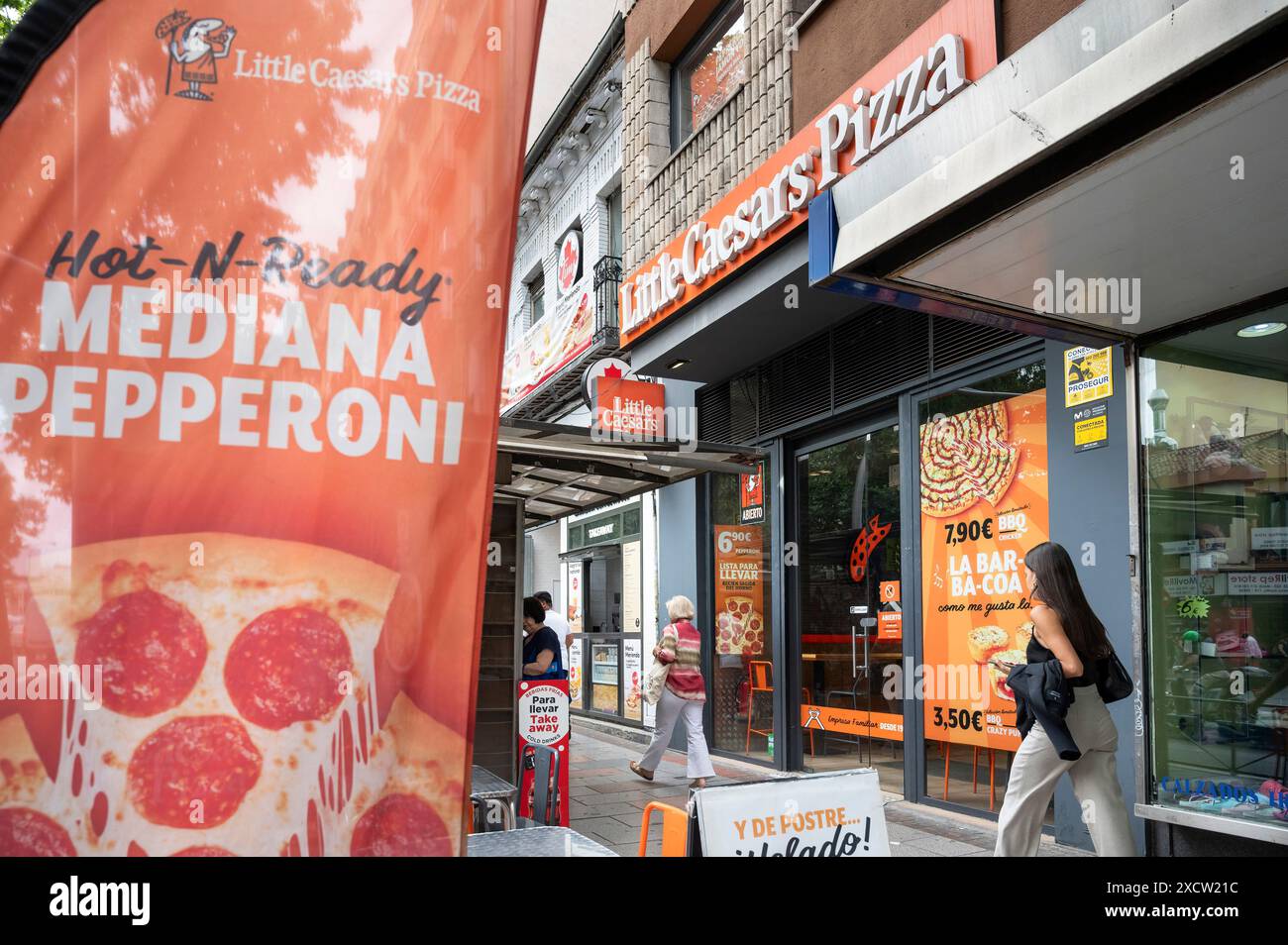 Fußgänger spazieren vorbei an der drittgrößten Pizzarestaurant-Kette der USA, Little Caesars Pizza, Logo-Schild in Spanien. Stockfoto