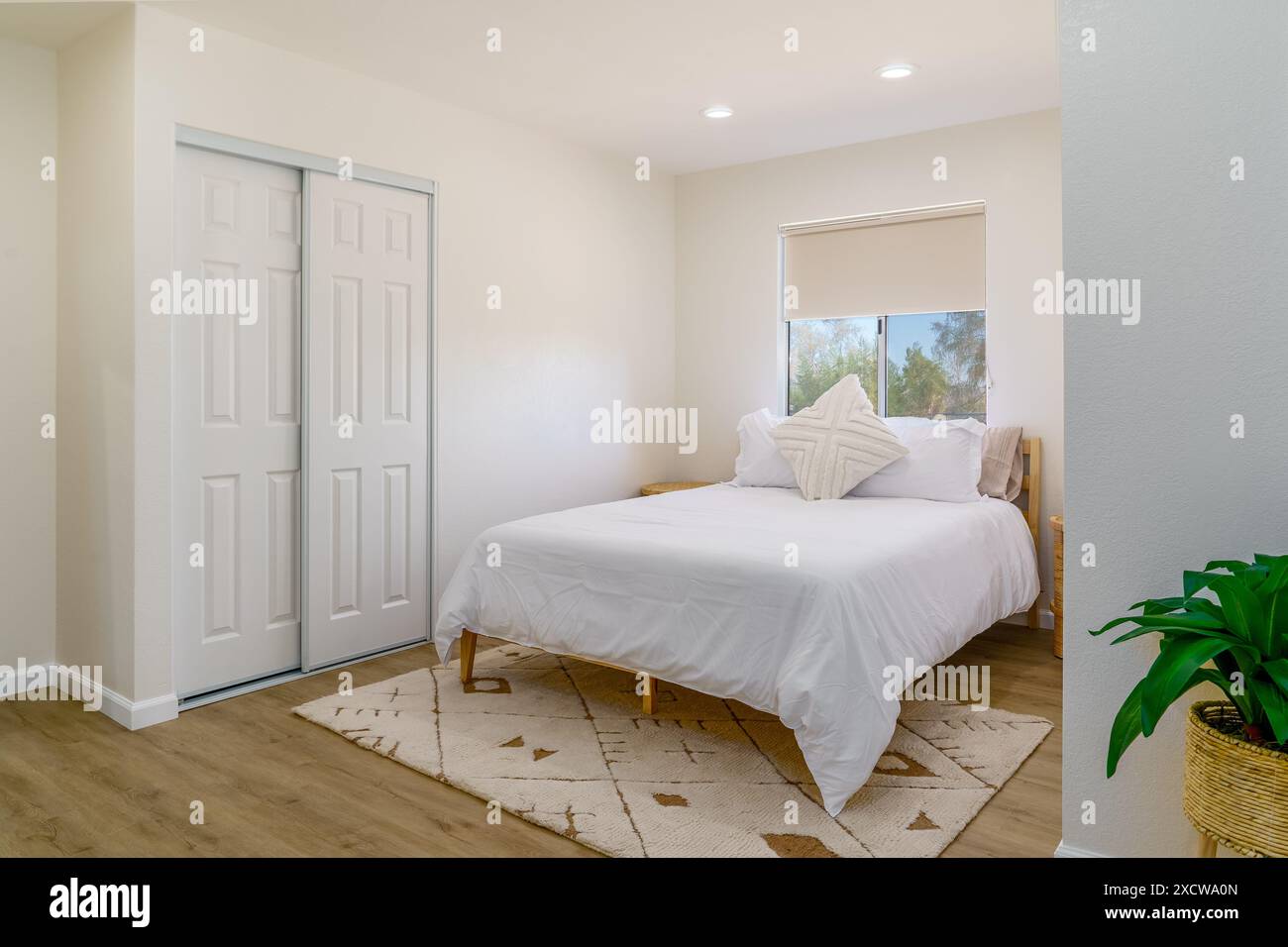 Modernes Bohemian Schlafzimmer innen weiß mit Bettteppich und Korbbeistelltisch Wüstenheim Stockfoto