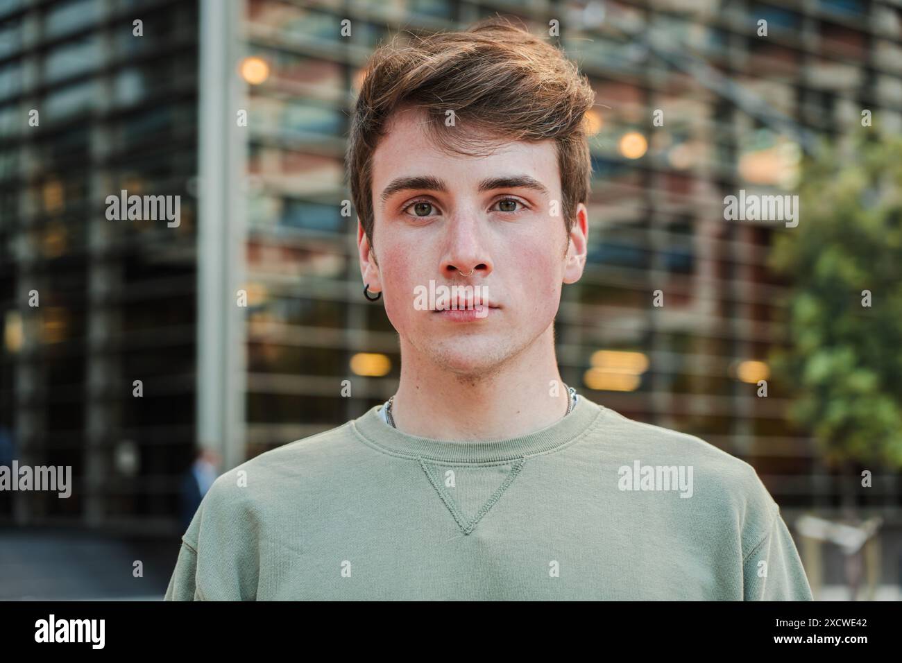 Nahaufnahme eines individuellen Porträts eines jungen männlichen Stands draußen und Blick in die Kamera mit ernstem Ausdruck. Teenager-Student starrt mit nachdenklicher Haltung nach vorne. Kopfaufnahme eines isolierten echten Typen. Hochwertige Fotos Stockfoto