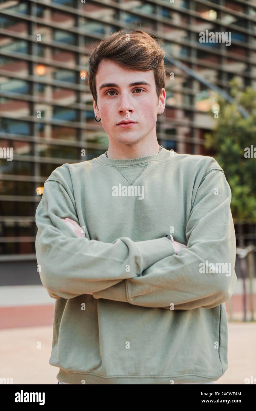 Vertikales Einzelporträt eines jungen männlichen Stands draußen und Blick in die Kamera mit ernstem Ausdruck. Teenager-Student starrt mit nachdenklicher Haltung nach vorne. Kopfaufnahme eines isolierten echten Typen. Hochwertige Fotos Stockfoto