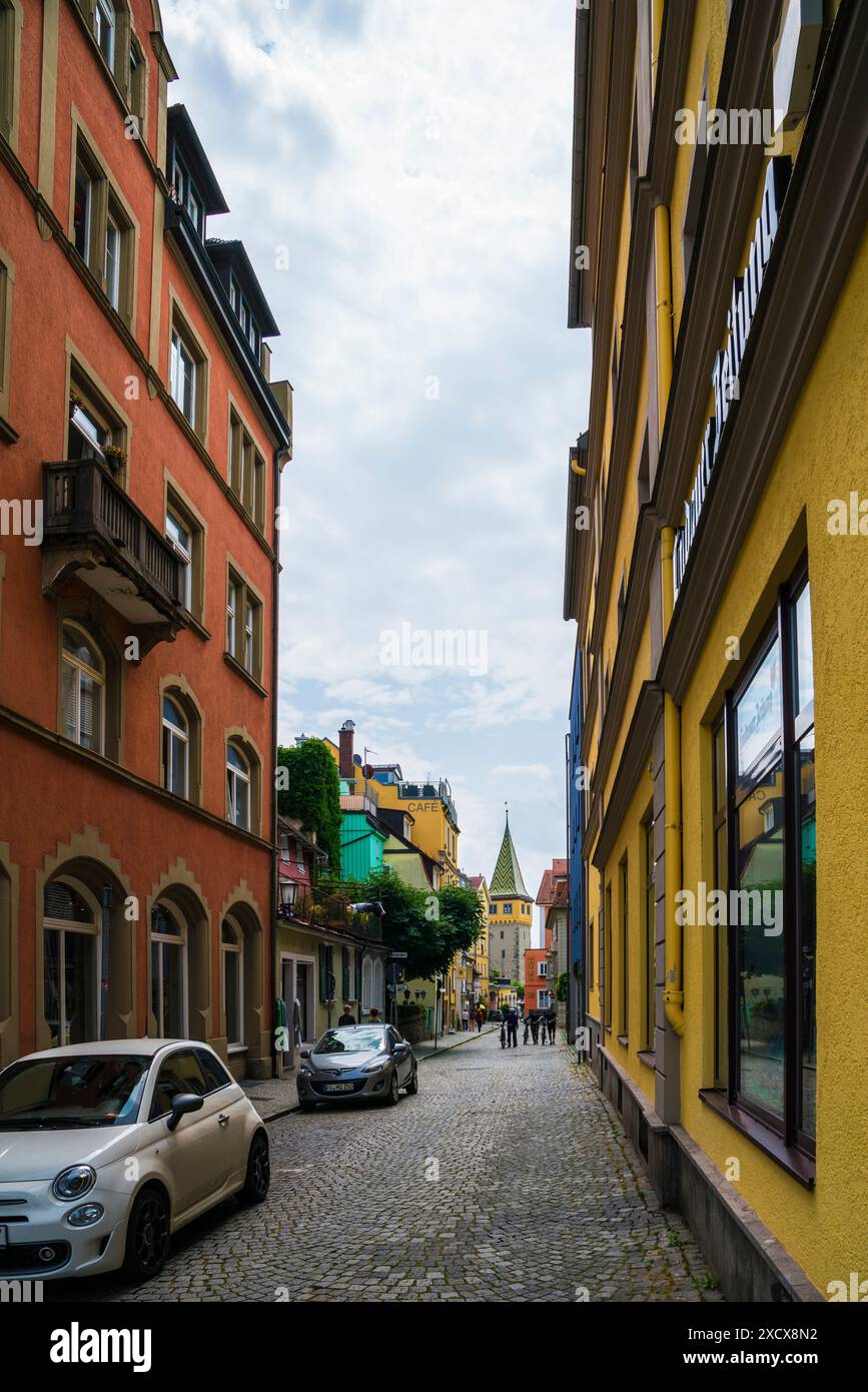 Lindau, Deutschland, 23. Juni 2023, bunte Altstadtfassaden in schmaler Straße mit Blick auf den Mangturturm im Hafen des Dorfes Stockfoto