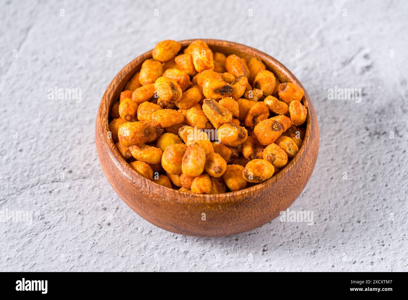 Geröstete Maisnüsse mit Soße in einer Holzschale auf weißem Steintisch Stockfoto