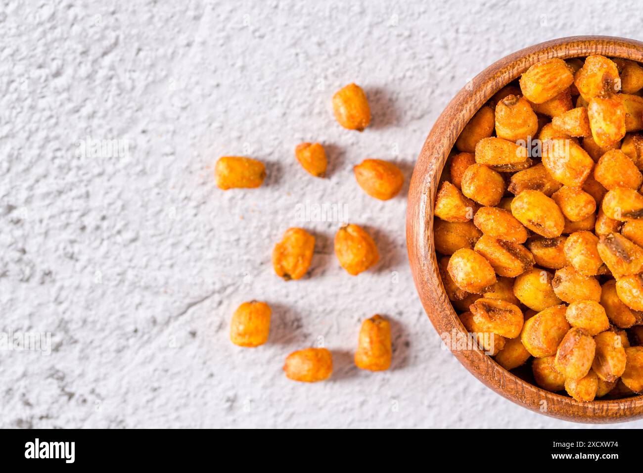 Geröstete Maisnüsse mit Soße in einer Holzschale auf weißem Steintisch Stockfoto