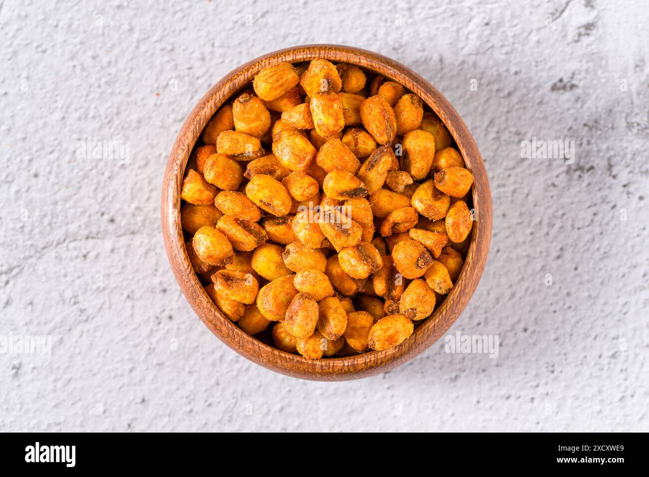 Geröstete Maisnüsse mit Soße in einer Holzschale auf weißem Steintisch Stockfoto