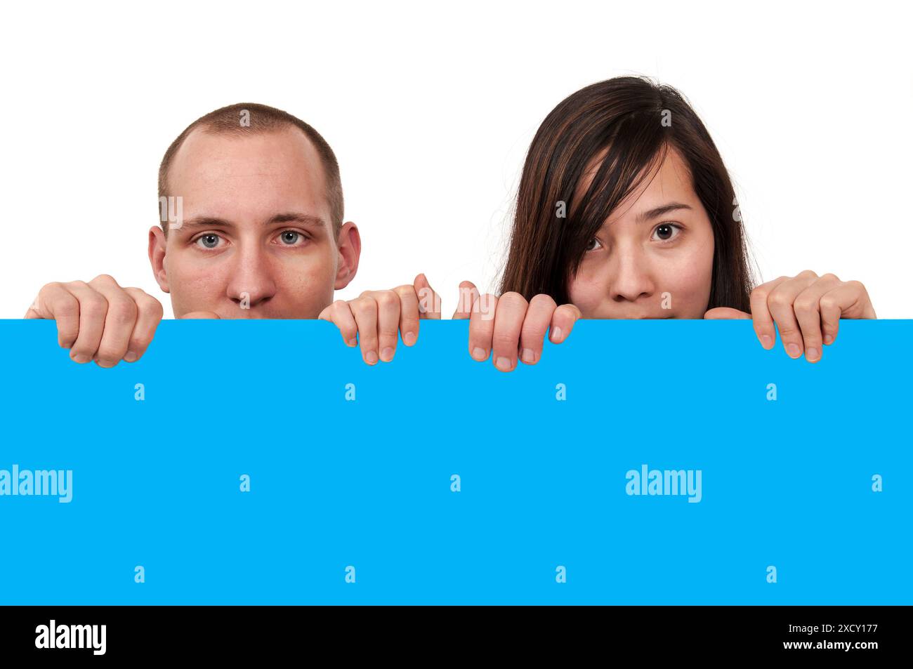 Frontale Kopfansicht eines jungen Paares, das vor seinem Gesicht einen einfarbigen leeren Raum bis zum Mund hält, vor einem weißen Hintergrund. Stockfoto