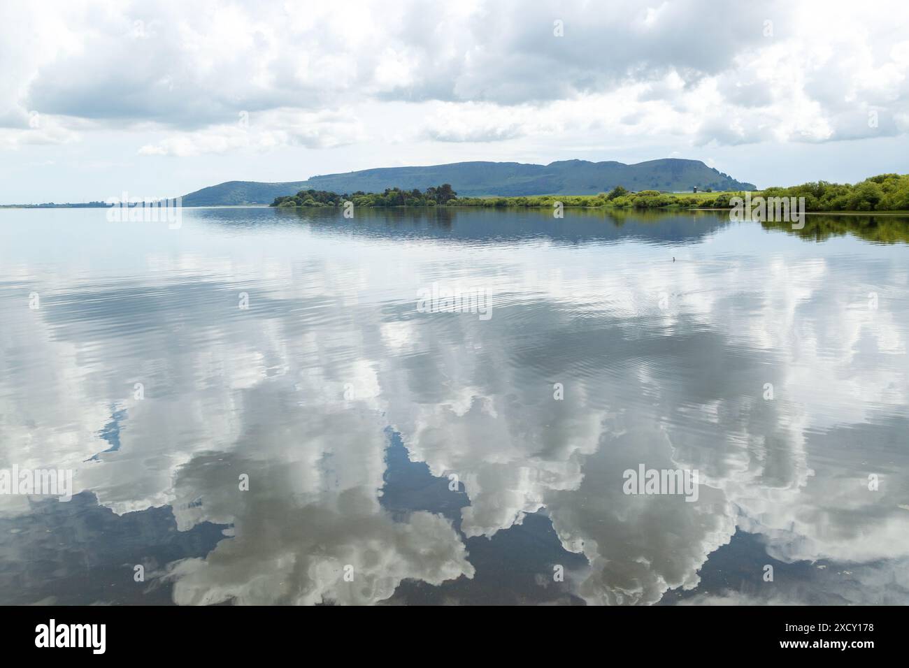 Wolken spiegeln sich auf dem ruhigen Wasser von Loch Leven mit Benarty Hill im Hintergrund Stockfoto