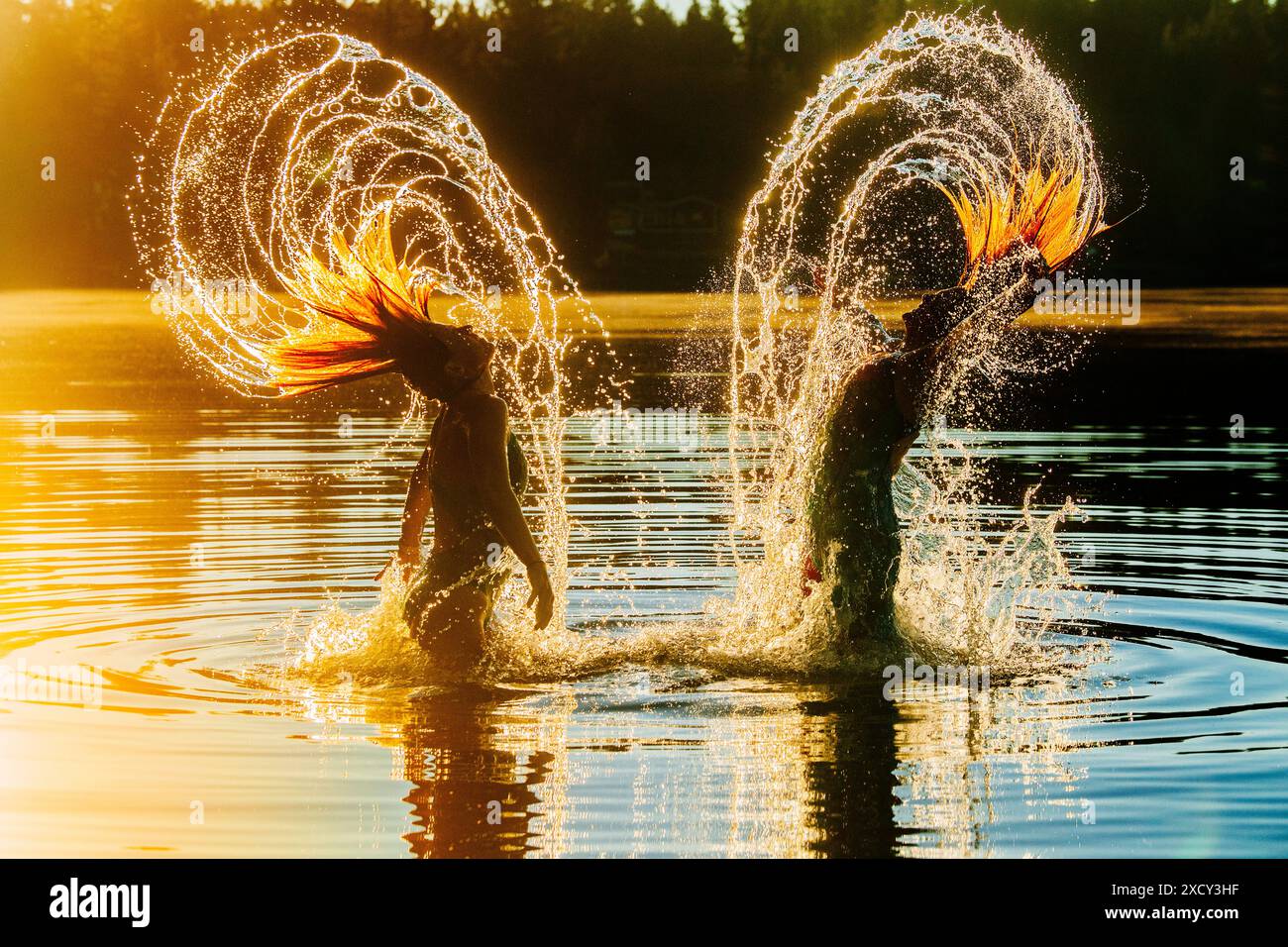 Zwei junge Frauen planschen in der Abenddämmerung im See Stockfoto