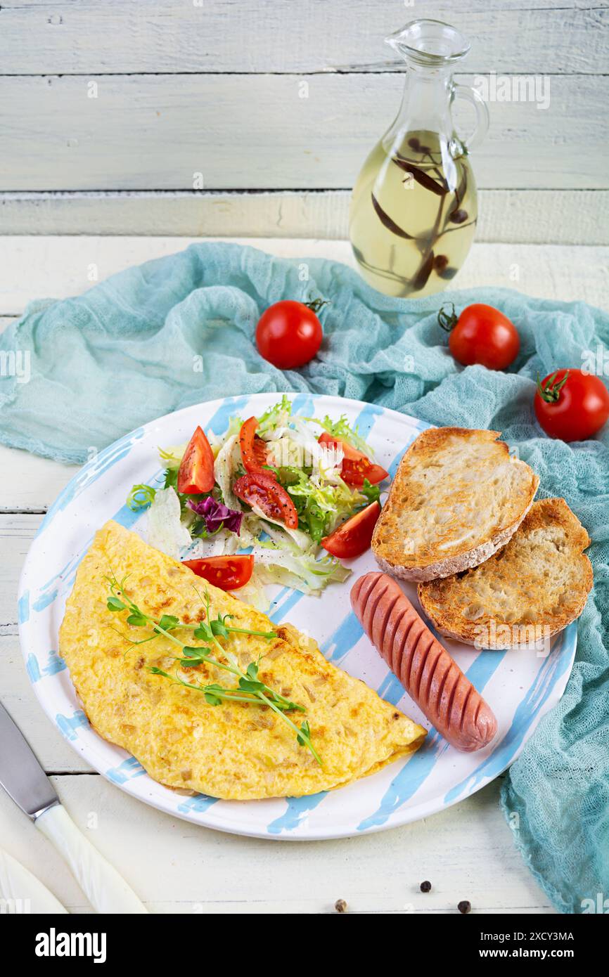 Gebratenes Omelette mit Wurst und Salat. Leckeres Frühstück mit Eiern und Toast Stockfoto