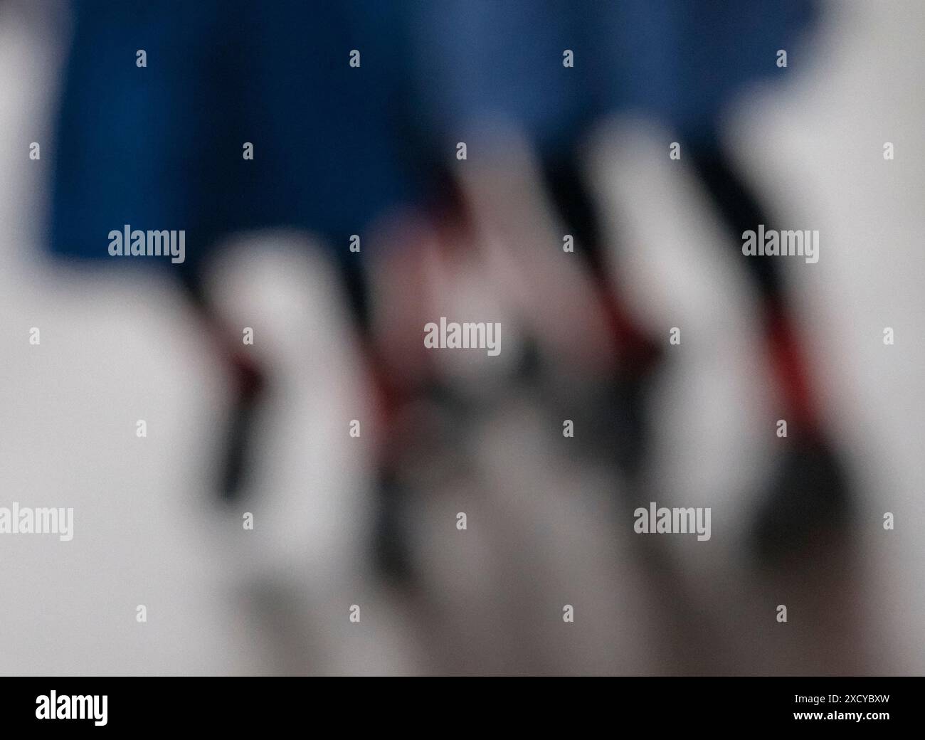 Drei Schulmädchen, die zur Schule gehen, tragen blaue Röcke und rote Socken. Absichtlich unscharfes Foto, um Schülerinnen abstrakt zu illustrieren Stockfoto