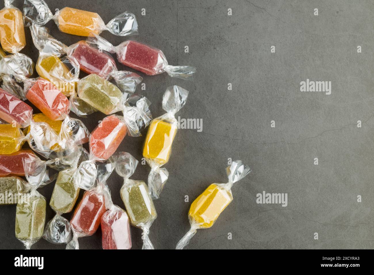 Verschiedene eingewickelte Gelee-Bonbons auf grauem Tisch, Draufsicht. Stockfoto