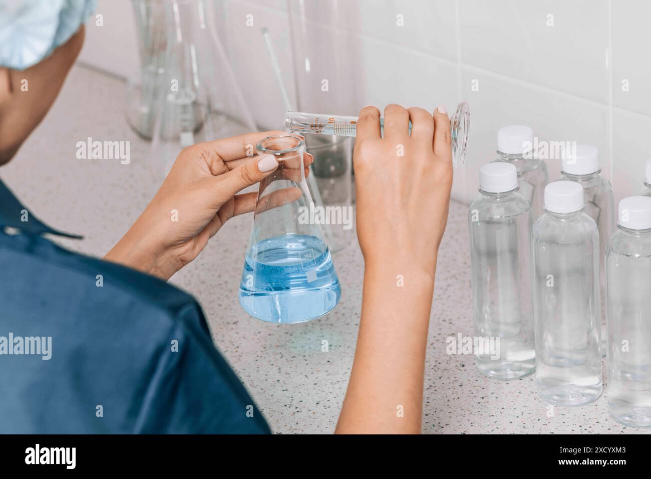 Frauen im Labor untersuchen die Wasserqualität mit einer mit Glasröhrchen gefüllten blauen chemischen Flüssigkeit für Forschung und Analyse im Labor Stockfoto