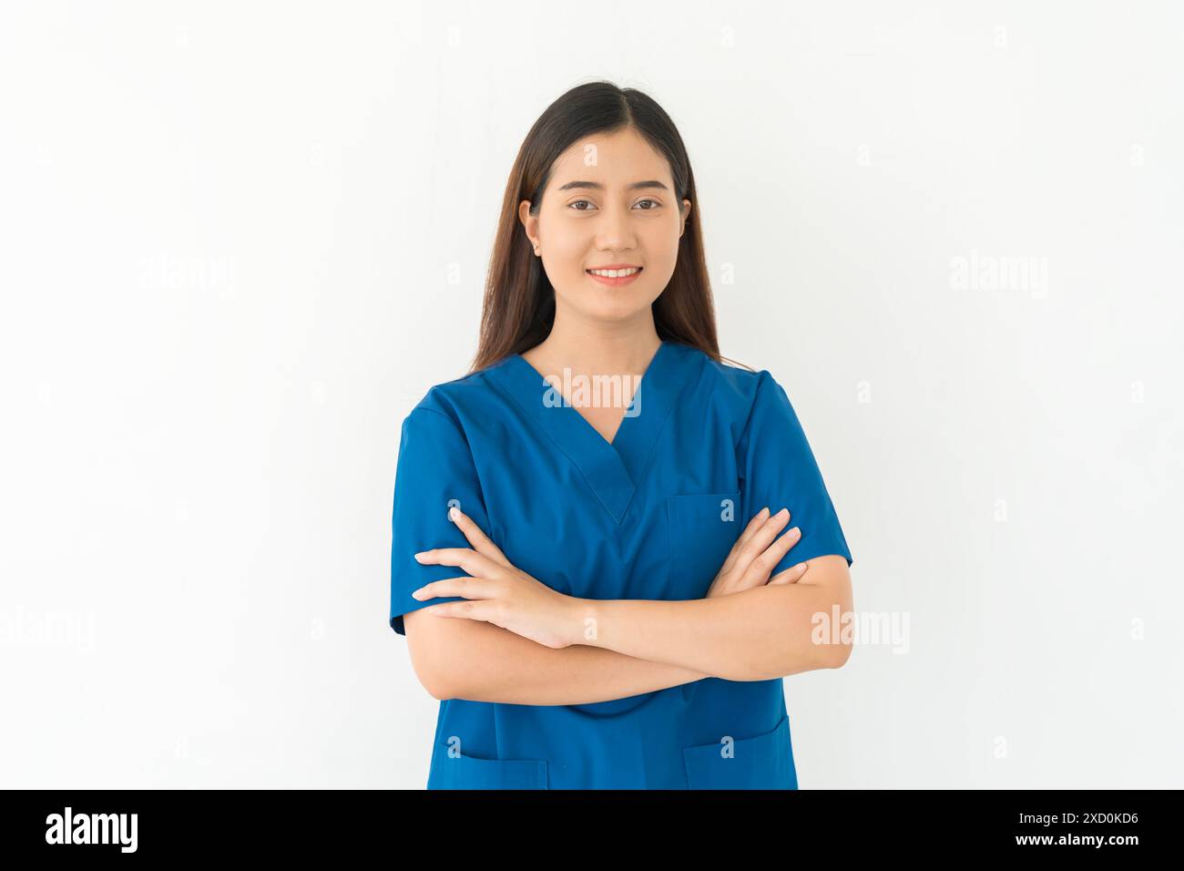 Eine Frau in einem blauen Hemd lächelt und kreuzt ihre Arme. Sie ist Krankenschwester oder Ärztin auf weißem, isoliertem Hintergrund Stockfoto