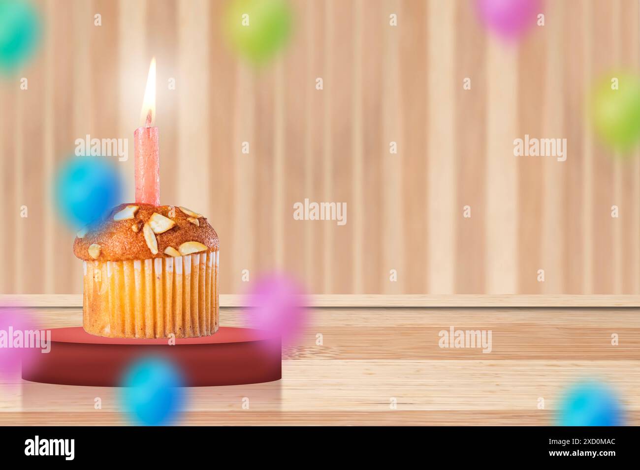 Geburtstagskuchen mit brennender Kerze auf hölzernem Hintergrund mit bunten Ballons. Kopierbereich. Stockfoto