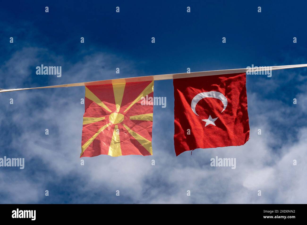 Einheit in Vielfalt. Die Fahnen der Türkei und Mazedoniens hängen zusammen. Blauer Himmel mit Wolken als Hintergrund. Stockfoto
