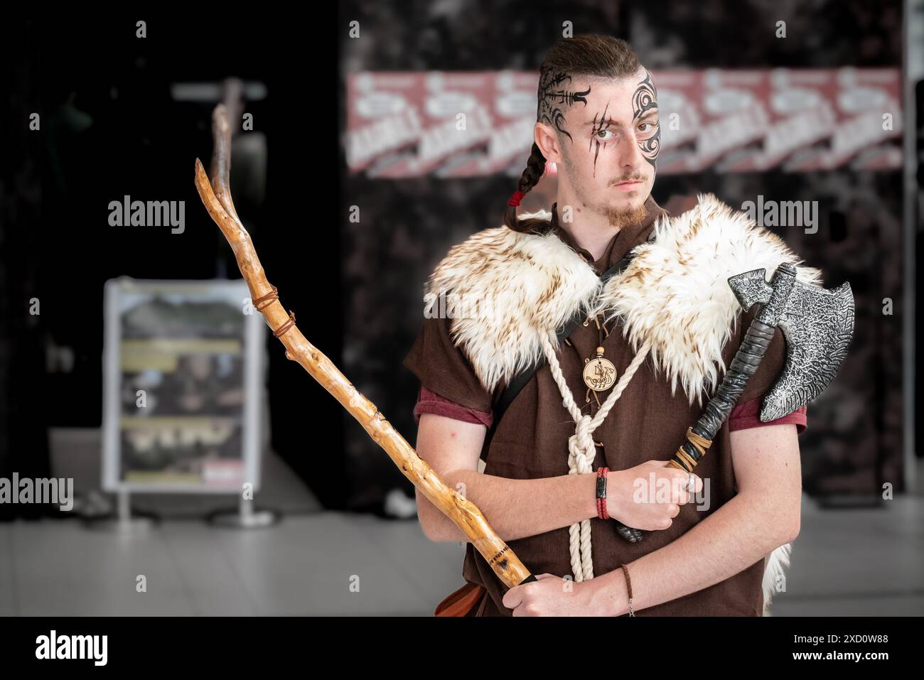 Ein junger Mann in mittelalterlicher Kleidung, der einen Stab hält und eine Maske trägt Stockfoto