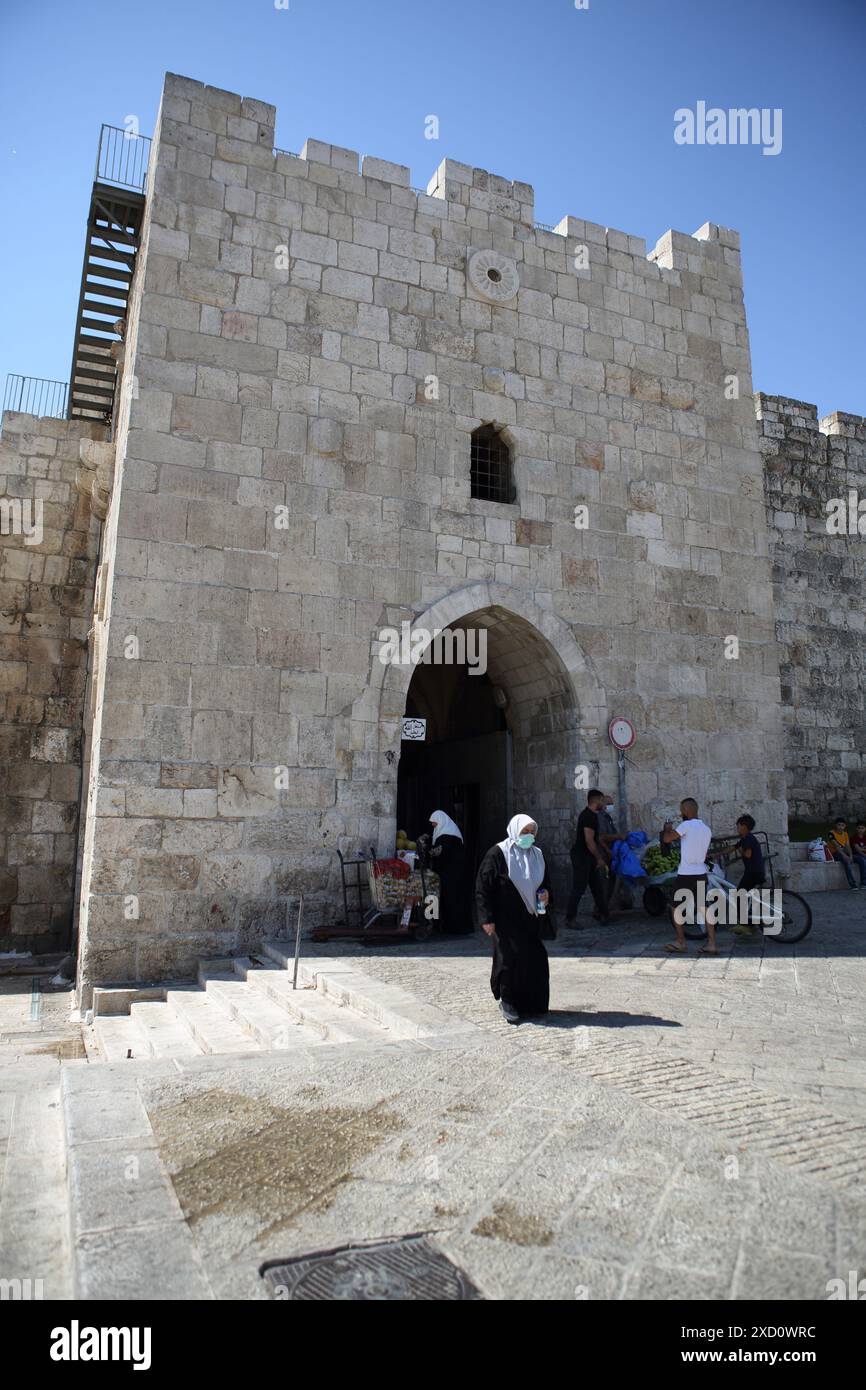 Frau, die Schutzmaske trägt wegen Corona Virus kommt aus Herodes Tor oder dem Blumentor, eines von acht Toren zur Altstadt von Jerusalem Stockfoto