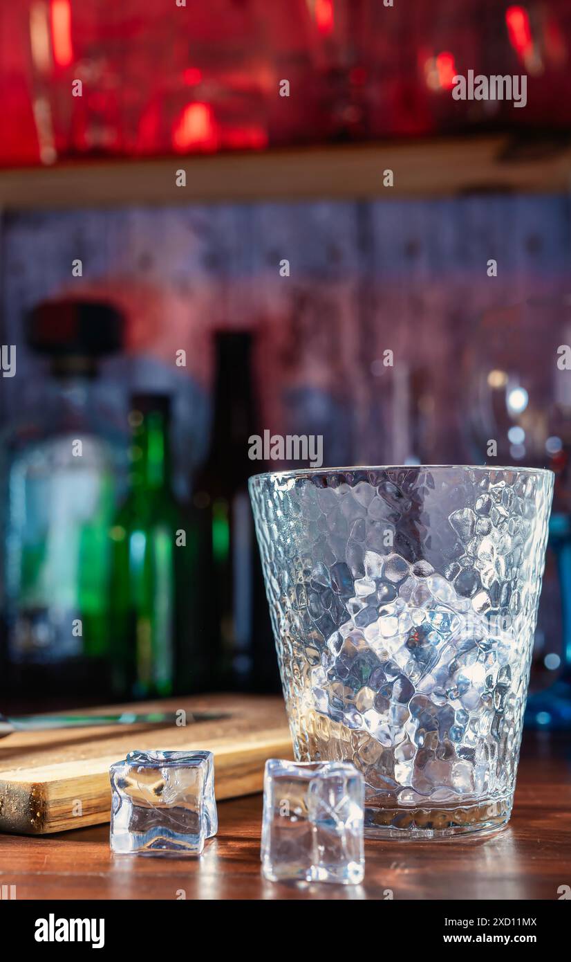 Glas mit Eis ohne Getränk, der Beginn eines tropischen und erfrischenden Getränks an der Bar. Cocktails, Rum, Wodka, nächtliche Atmosphäre, Party und frische Getränke Stockfoto