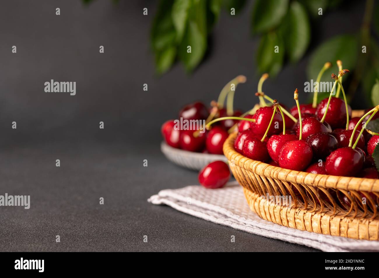 Nahaufnahme eines Korbkörpers, gefüllt mit frischen, roten Kirschen, auf einem Tuch Stockfoto