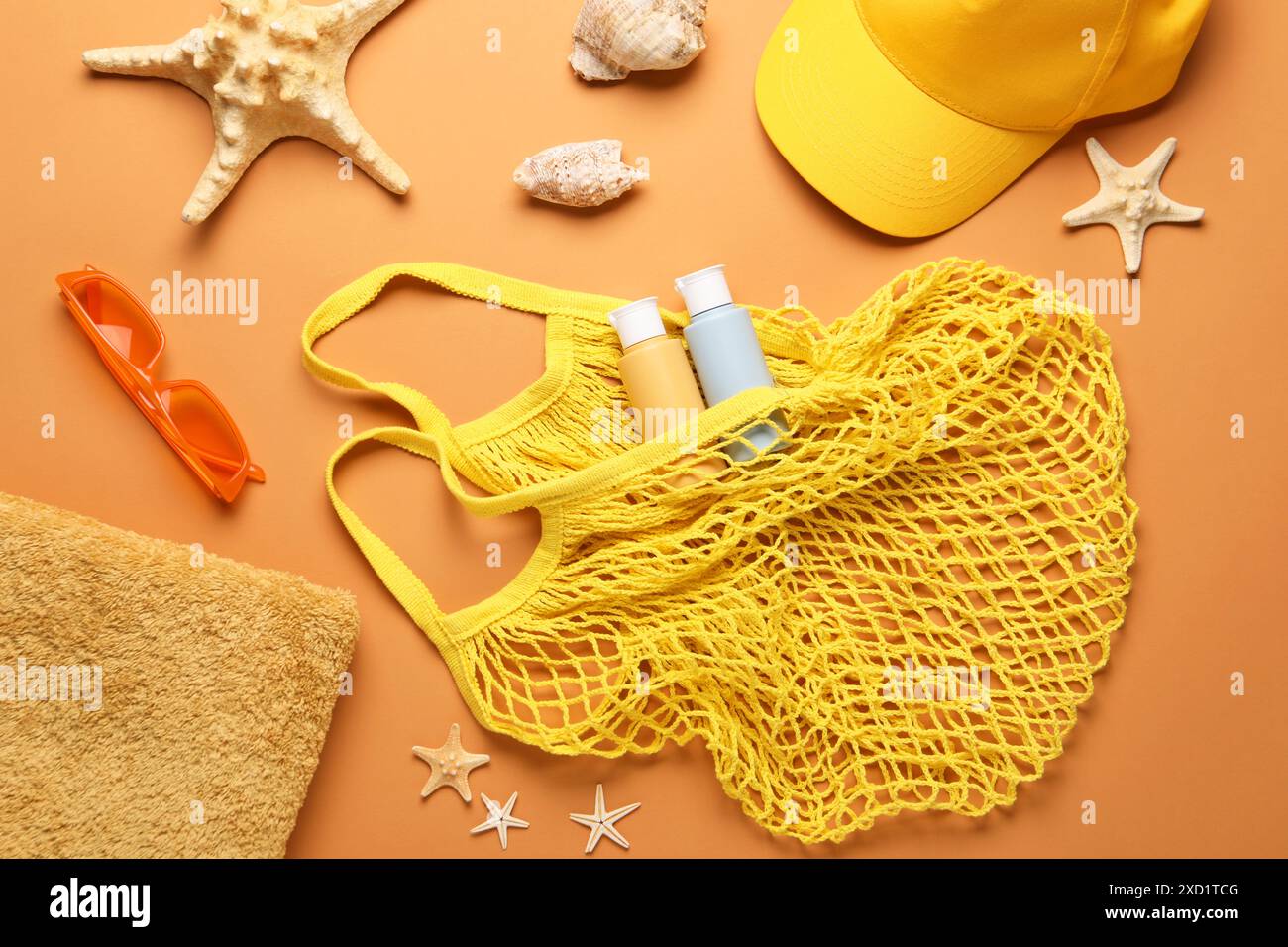 Schnur-Tasche und verschiedene Strandzubehör auf hellorangem Hintergrund, flach gelegt Stockfoto