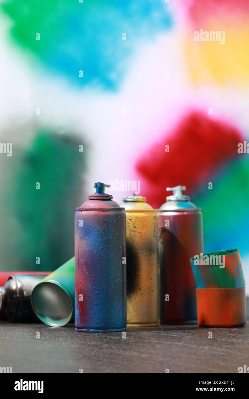 Viele Sprühdosen auf grauer Oberfläche vor farbigem Hintergrund Stockfoto