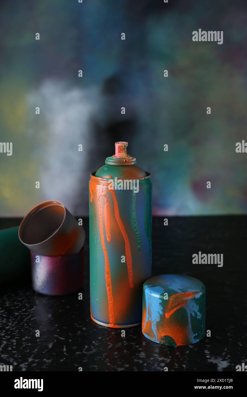 Lackdose und Kappen auf schwarze strukturierte Oberfläche vor farbigem Hintergrund sprühen Stockfoto