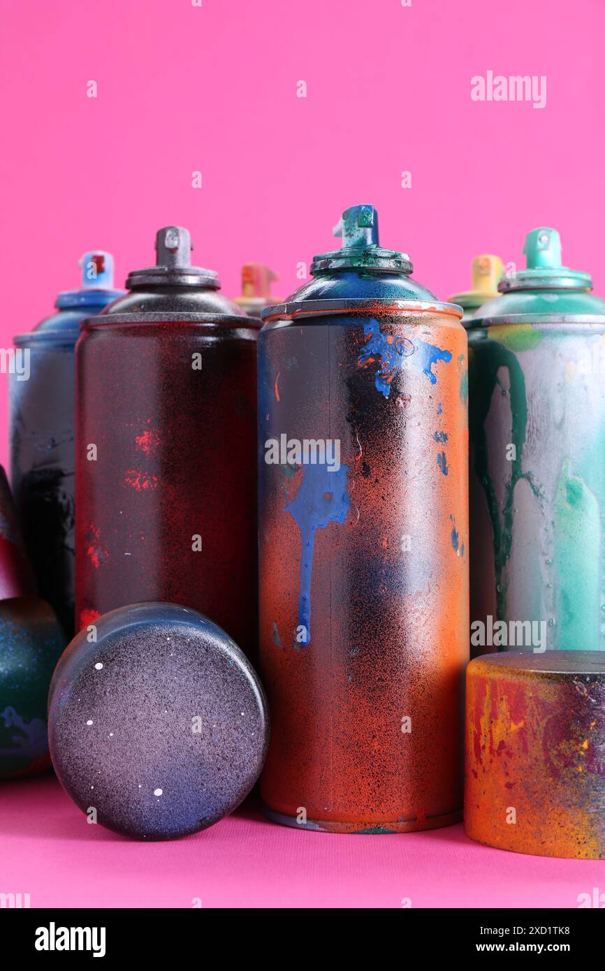 Viele Sprühdosen mit Kappen auf rosa Hintergrund, Nahaufnahme Stockfoto