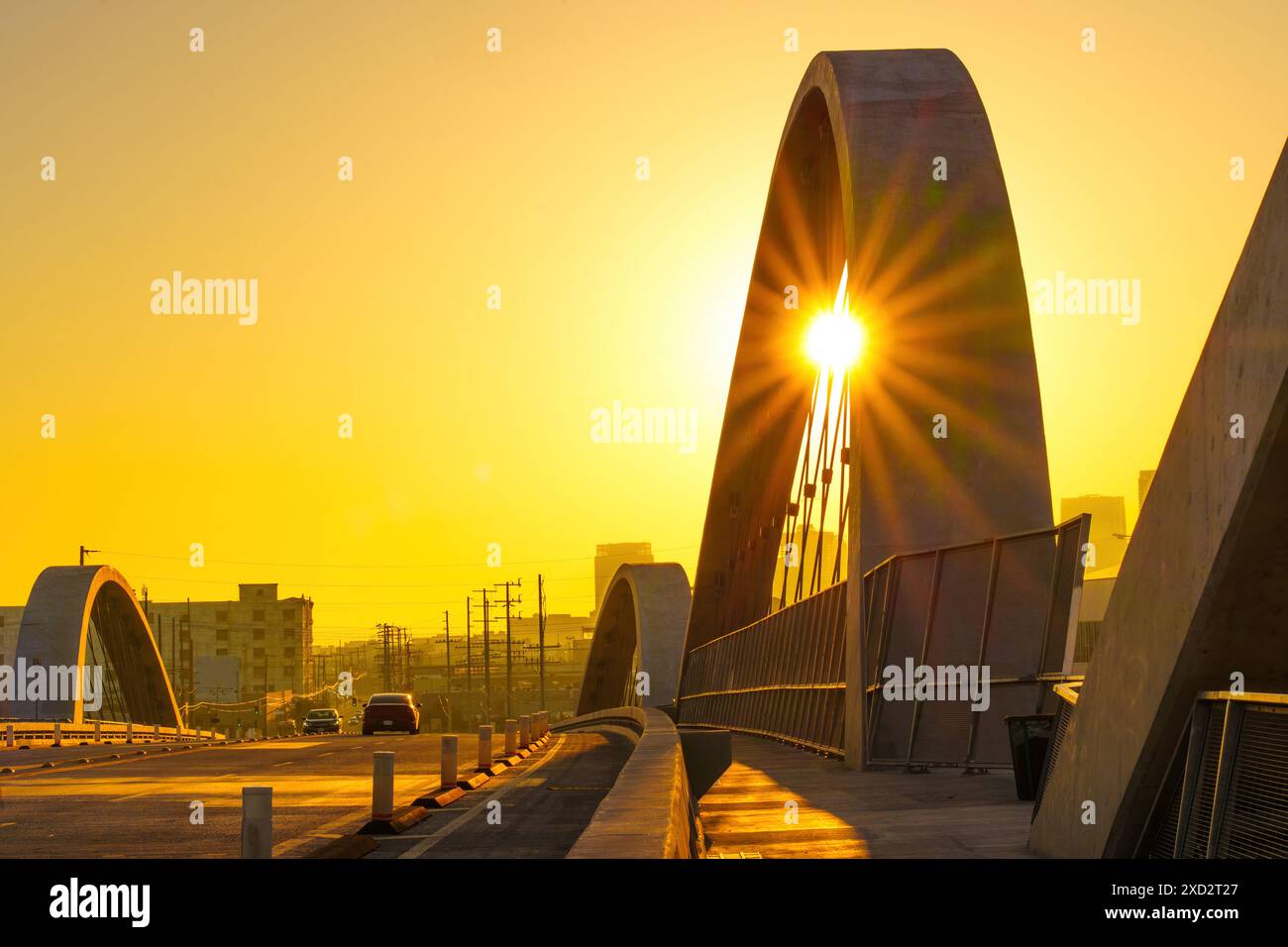 Die berühmte 6th Street Bridge in Los Angeles während der Dämmerung mit Autos, die über die Sonne fahren und goldene Töne strahlen. Stockfoto