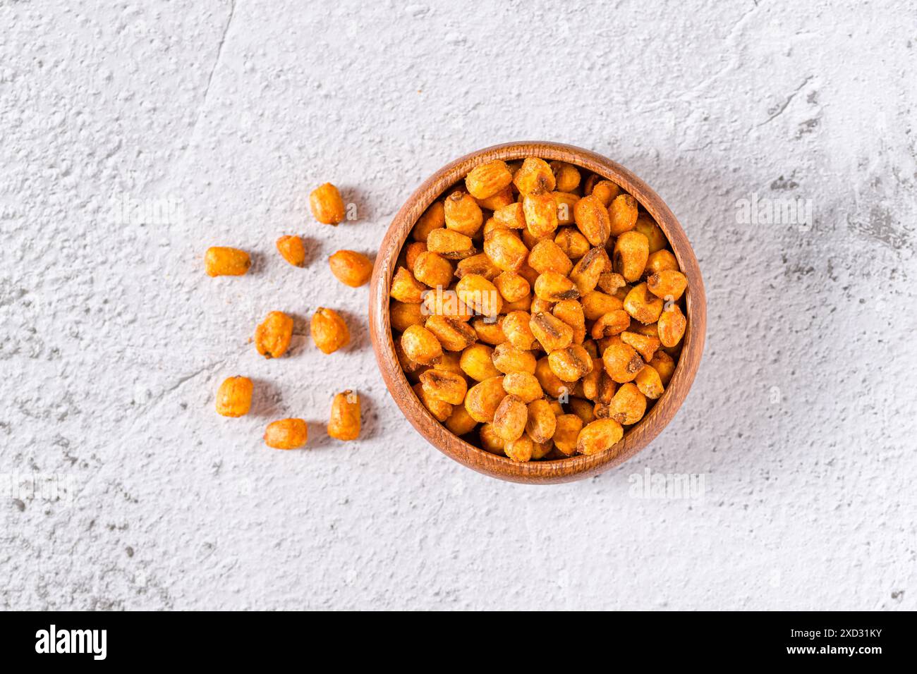 Geröstete Maisnüsse mit Soße in einer Holzschale auf weißem Steintisch Stockfoto