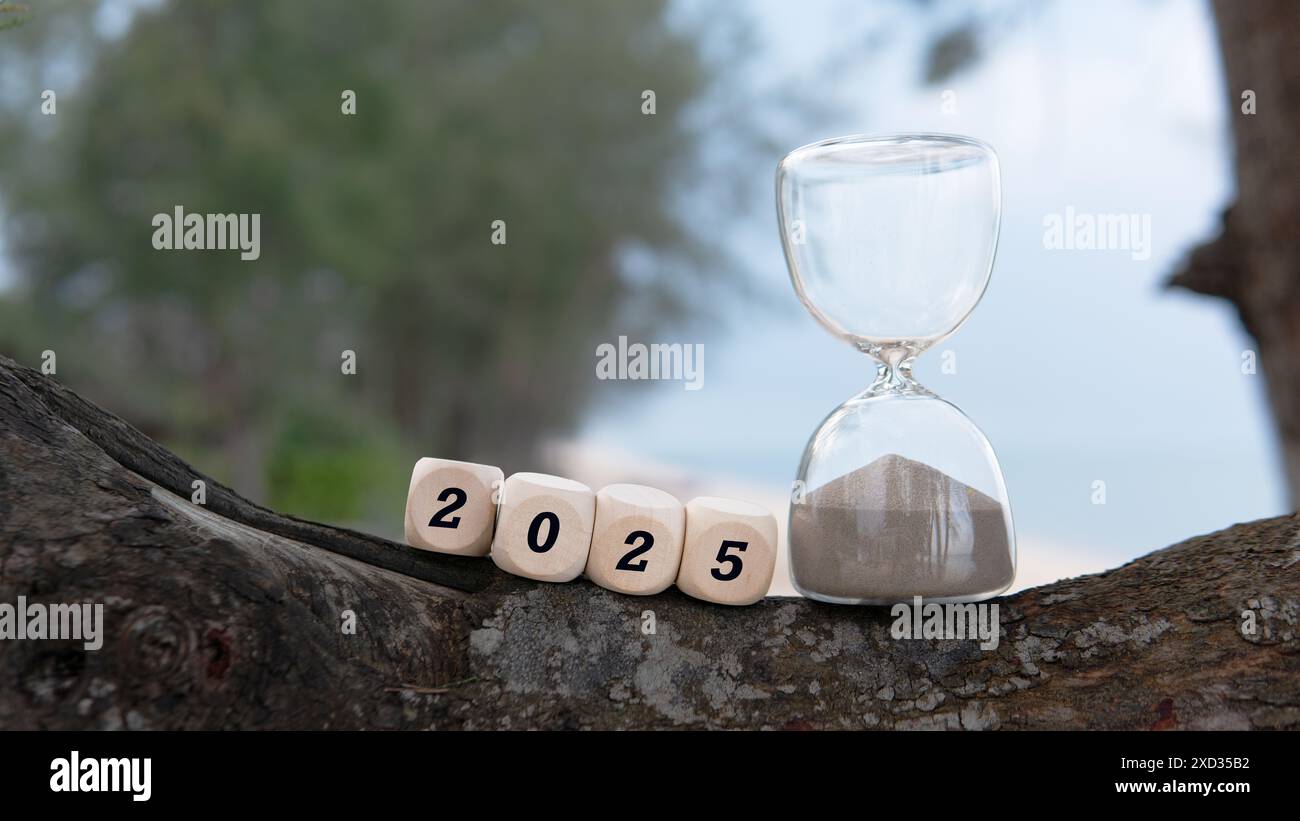 Ein Stundenglas mit einem Würfelwürfel und einem Text 2025 als Symbol dafür, dass das Jahr 2024 dem Ende naht und das Jahr 2025 sich dem Horizont nähert. Stockfoto