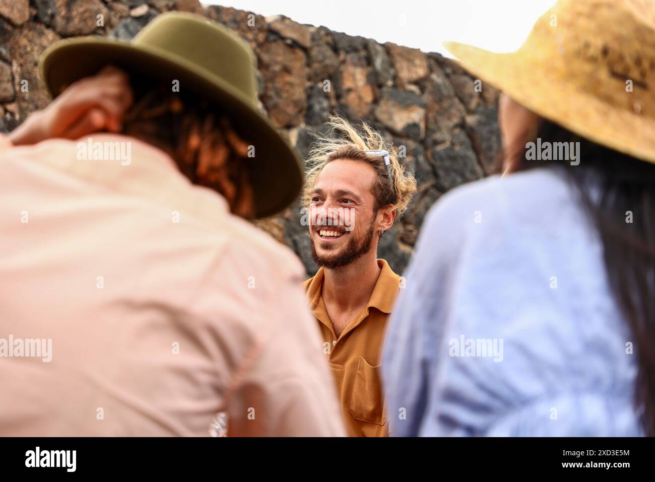 Multiethnische Gruppe von Freunden lacht und genießt ein Barbecue im Freien, mit einem kaukasischen Mann, der in die Kamera lächelt. Stockfoto