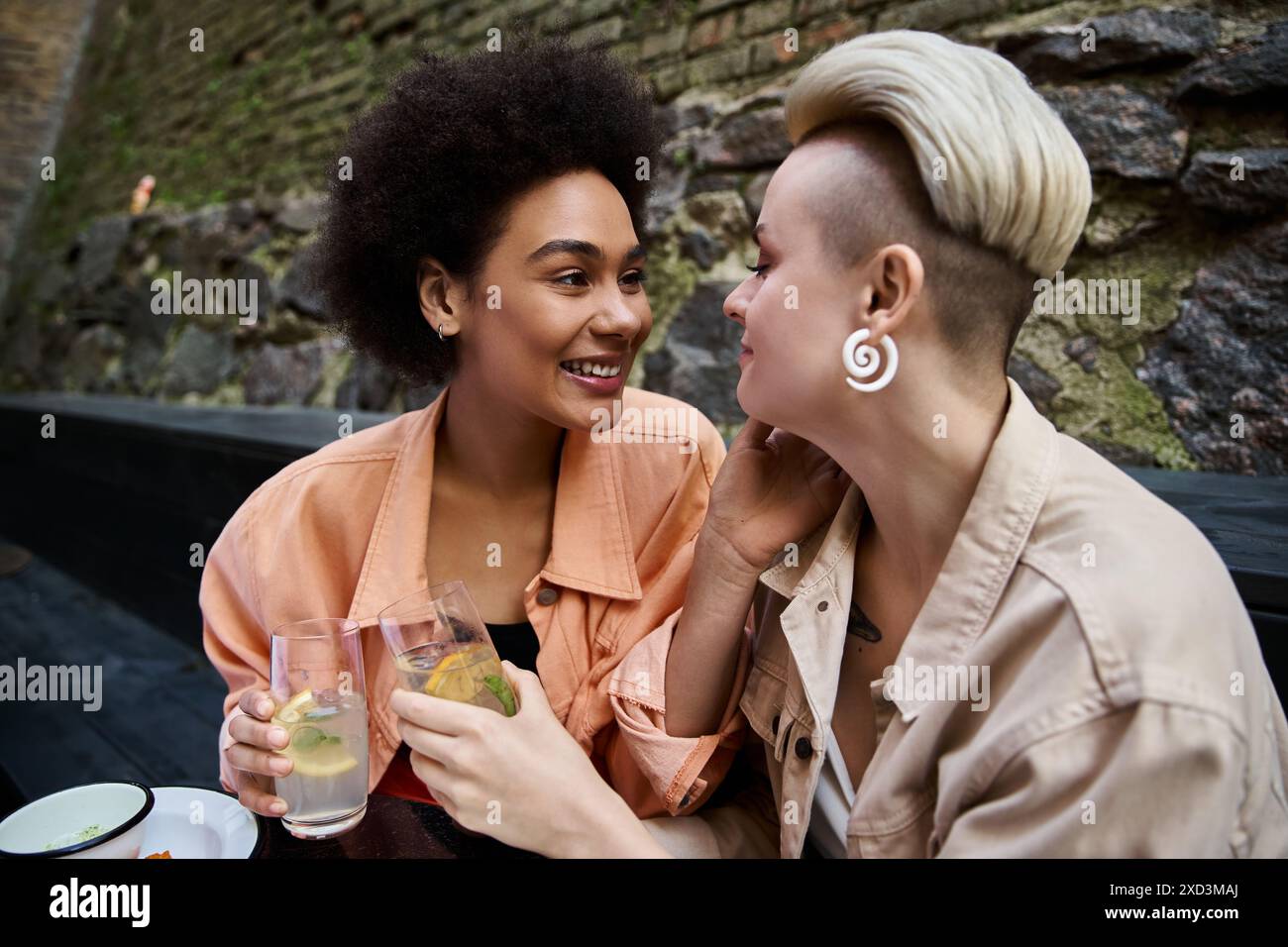 Zwei verschiedene Frauen genießen ein Date in einem gemütlichen Café, sitzen dicht und unterhalten sich. Stockfoto