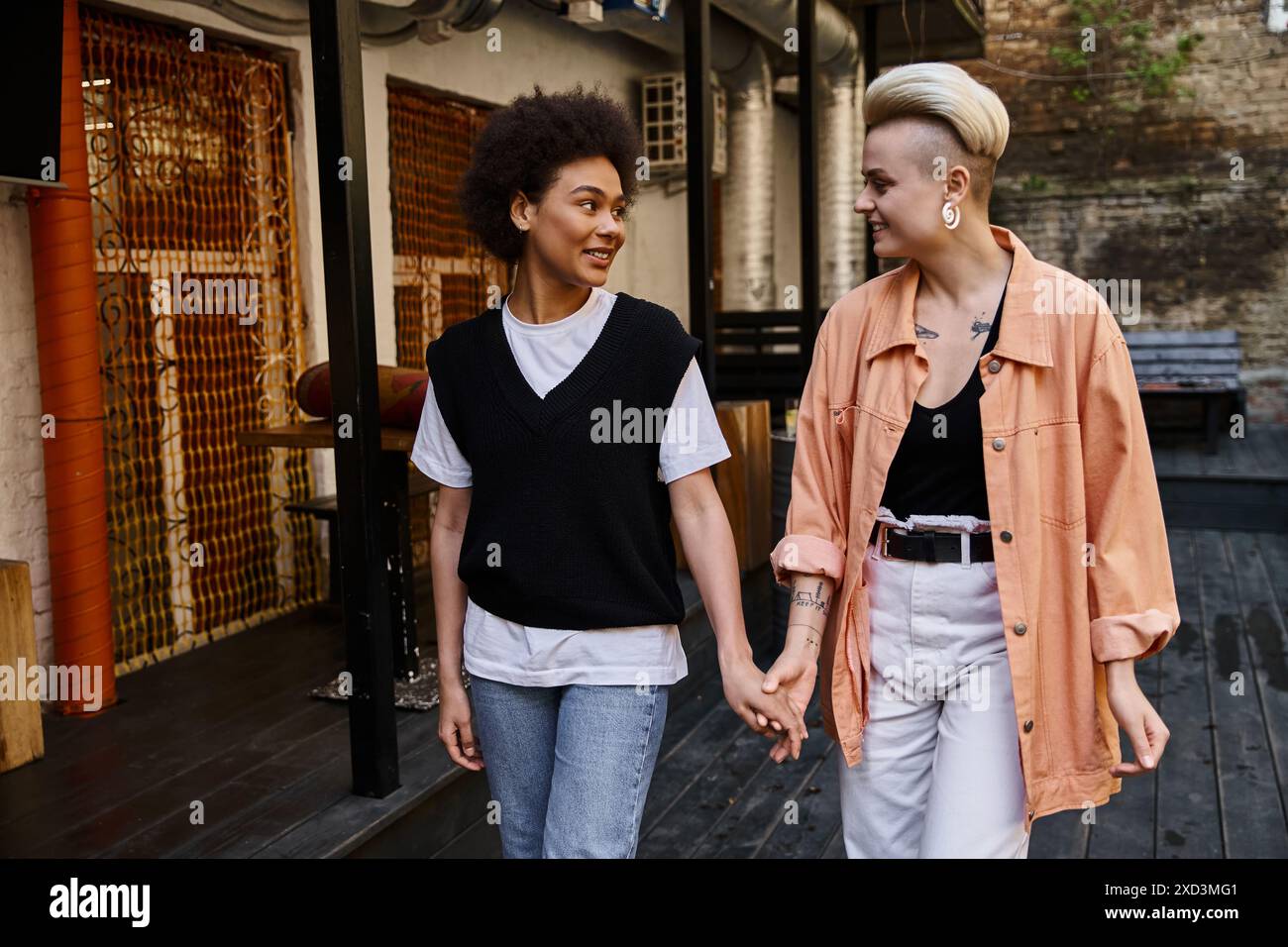 Verschiedene Lesben teilen einen intimen Moment, während sie Hand in Hand die Straße entlang laufen. Stockfoto