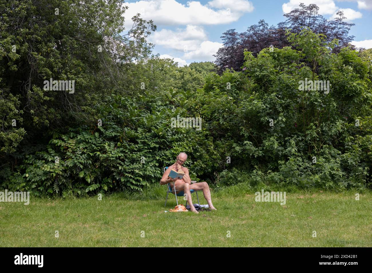 Ein Mann sitzt während einer Mini-Hitzewelle in London, England, Vereinigtes Königreich, in den Kensington Palace Gardens Stockfoto