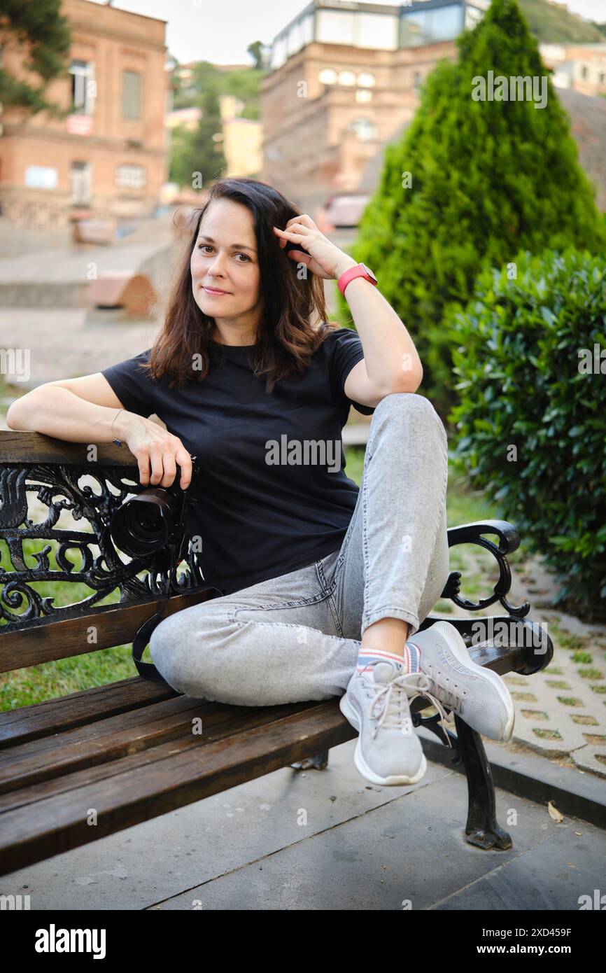 Eine Frau war in der antiken Stadt und setzte sich auf eine Bank im Schatten der Bäume Stockfoto