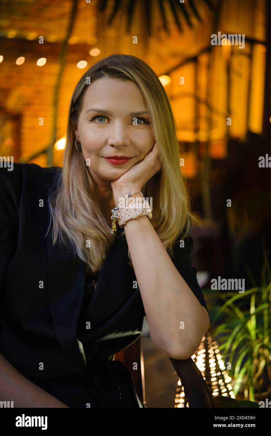 Abends im Freien Porträt einer ruhigen und positiven Frau mittleren Alters, die auf der Außenterrasse sitzt Stockfoto