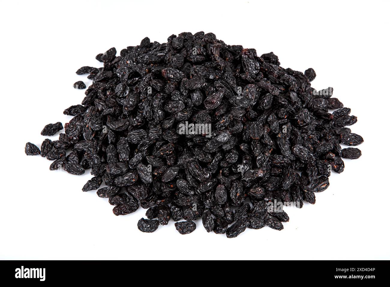 Schwarze Rosinen mit Samen (Sultaninen), getrocknete Früchte. Getrocknete schwarze Rosinen in einer Kupferschale, verstreute Rosinen um eine Kupferschale Rosinen. Stockfoto