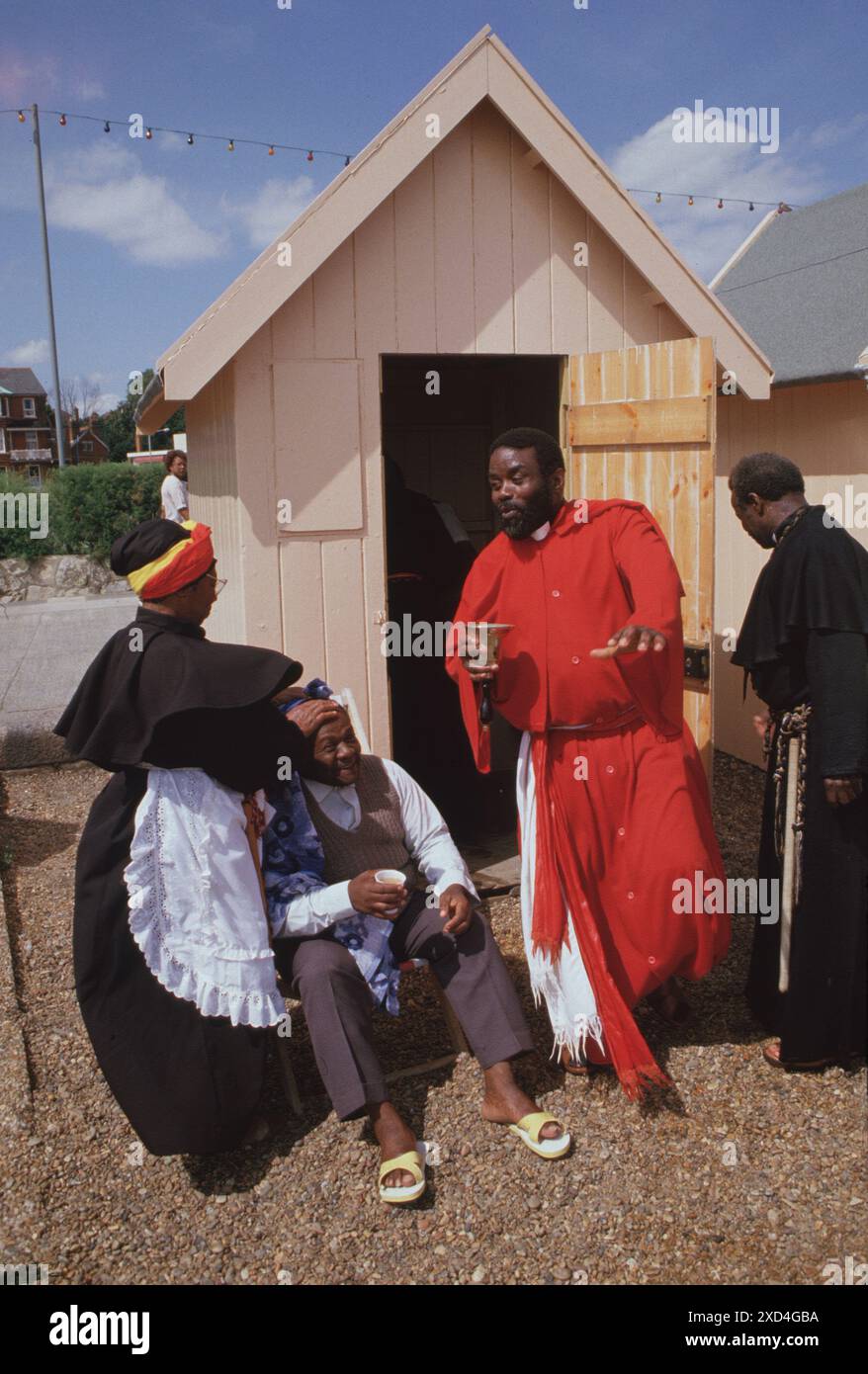 Mount Zion Spiritual Baptist Church, ein jährlicher Ausflug zum Felixstowe Beach, wo neue Mitglieder der Kirche getauft werden. Vater Noel mit heiligem Öl in der umgedrehten Glocke. Heiliges Öl wird in den Kopf des neuen Mitglieds gerieben, er wurde gerade getauft. Felixstowe, Suffolk, England 1990 1990er Jahre, UK HOMER SYKES Stockfoto