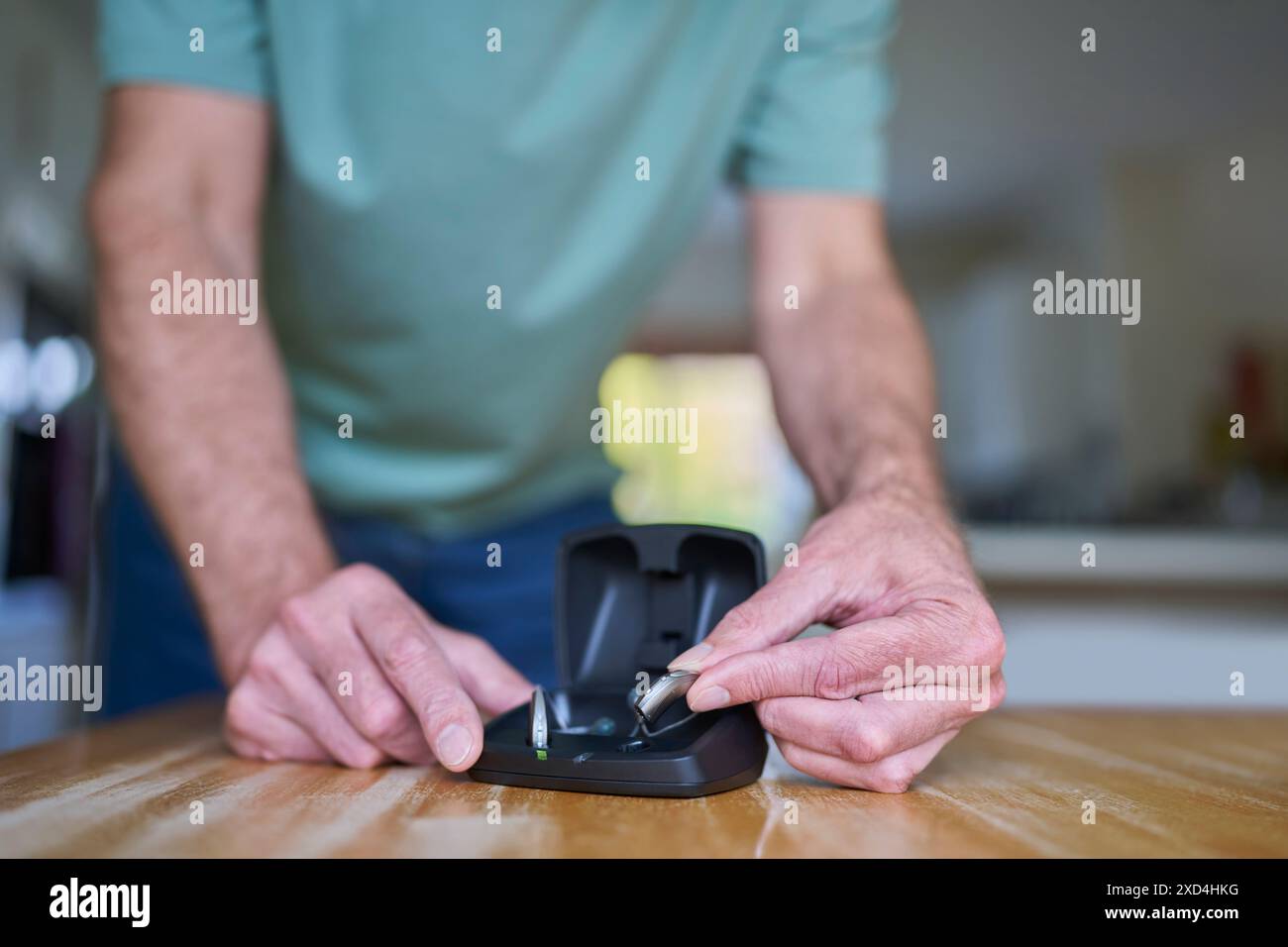 Nahaufnahme Eines Mannes, Der Zu Hause Ein Drahtloses Hörgerät Oder Gerät Aus Der Ladetasche Nimmt Stockfoto